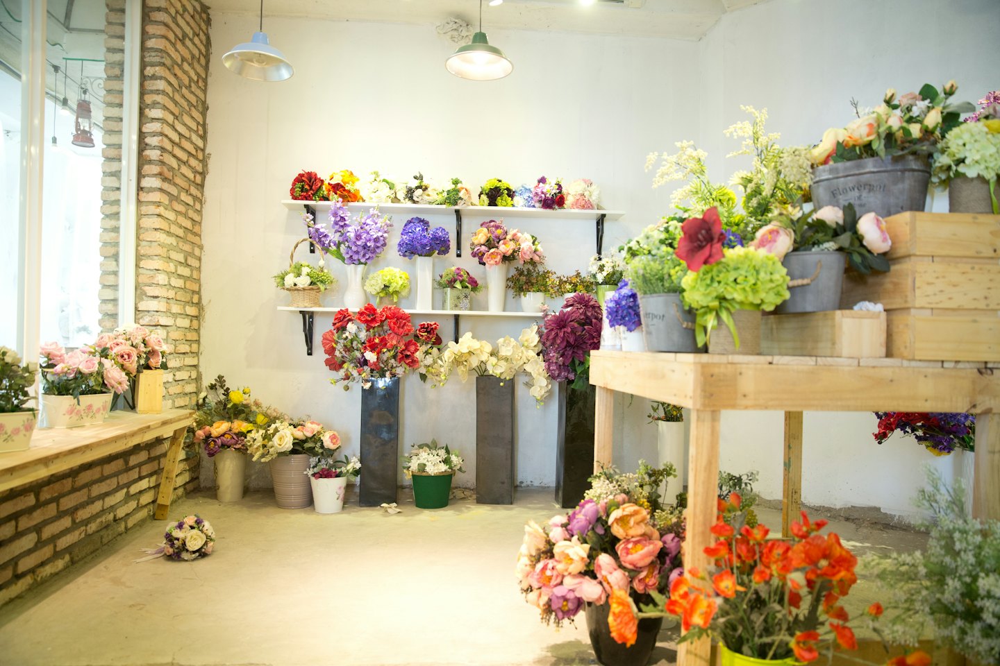 Färgglada konstgjorda blommor utställda i en ljus blomsterbutik.